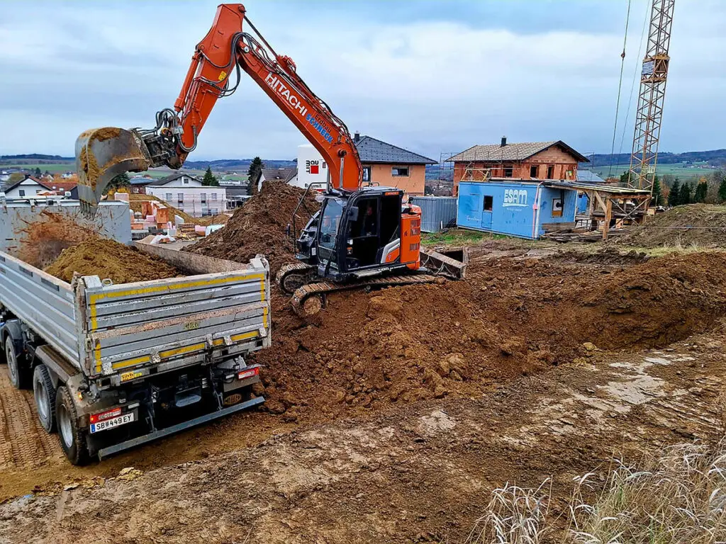 Baugrubenaushub für ein Wohnbauprojekt mit Bagger und Transportfahrzeug.
