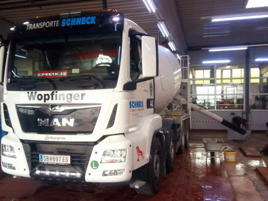 MAN-Fahrmischer von Schneck Transport & Erdbau in einer Werkshalle bei der Reinigung und Wartung des Fahrzeugs.