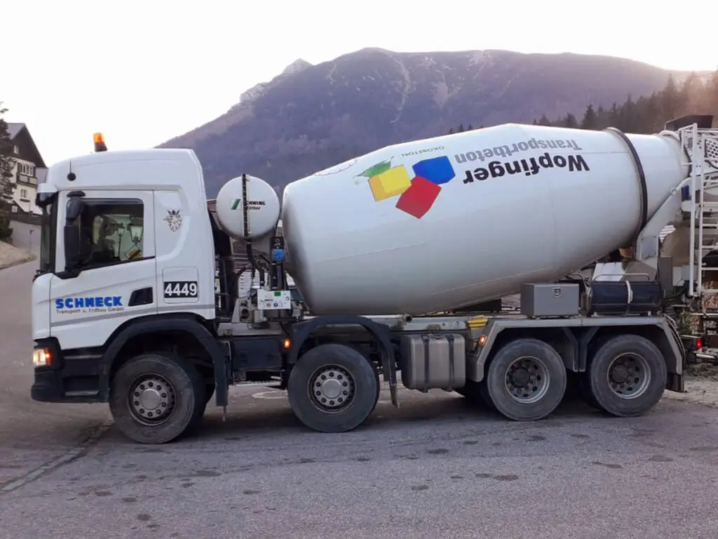 Seitenansicht eines Wopfinger-Fahrmischers beim Transport von Frischbeton zu einer Baustelle.