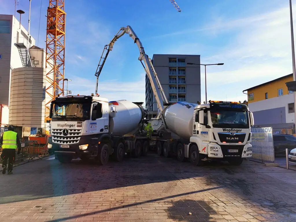 Betonierarbeiten auf einer Großbaustelle mit Fahrmischer und stationärer Betonpumpe beim Einbringen von Beton.