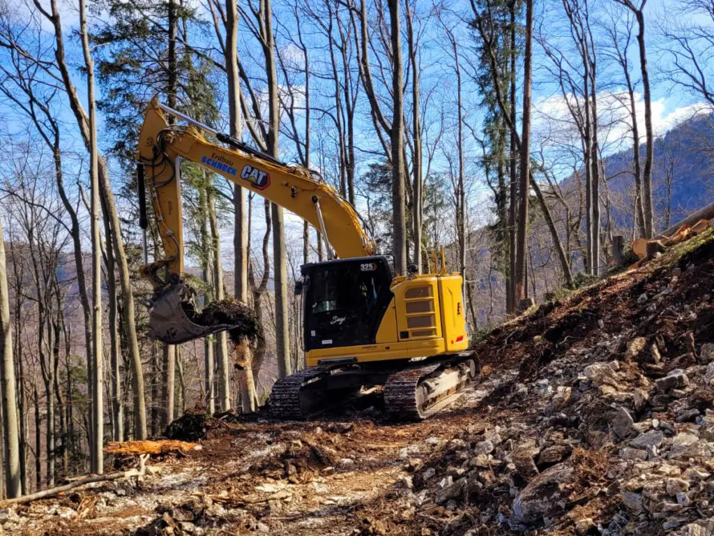 Forstwegebau mit Kettenbagger zur Geländeprofilierung im Waldgebiet.