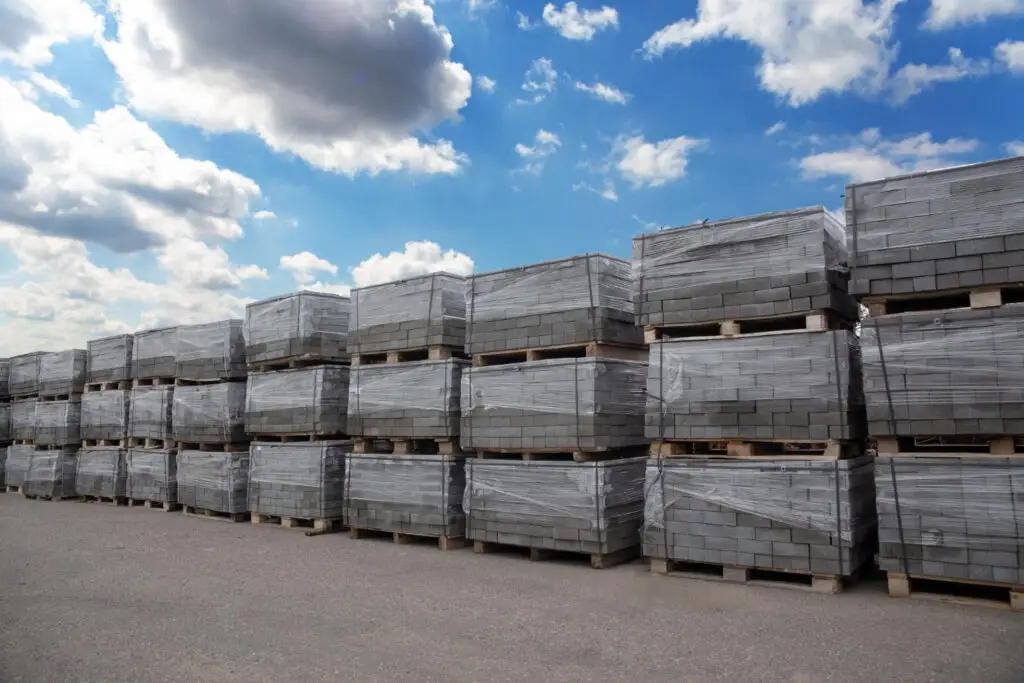 Mehrere Paletten mit Betonpflastersteinen und Pflastermaterialien auf einem Baustofflager zur späteren Auslieferung an Baustellen und Privatkunden.