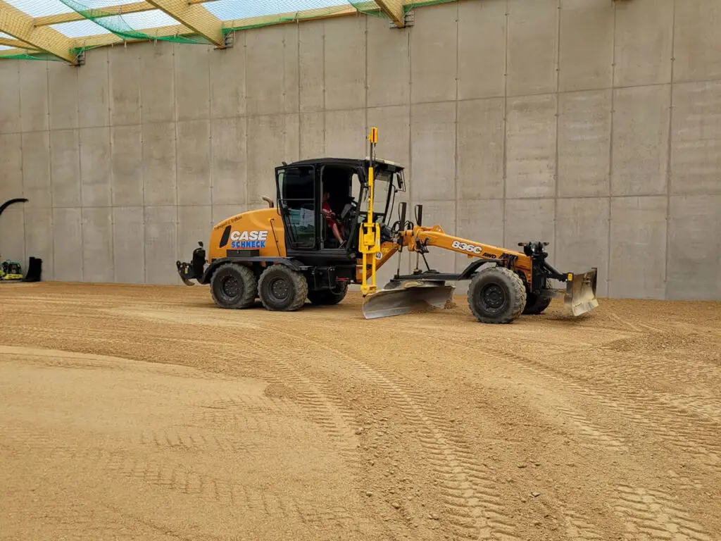 Motorgrader bei der Feinplanierung einer Hallen- oder Lagerfläche.