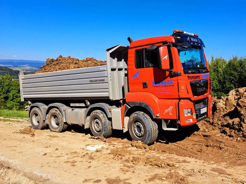 Vierachs-Kipper von Schneck beim Transport von Erd- und Steinmaterial auf einer Baustelle.