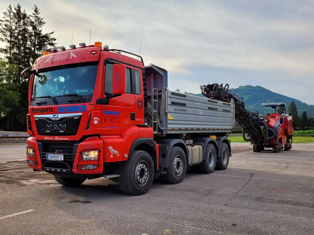 MAN-Kipper mit Ladekran beim Transport von Schotter, Steinen und Baumaterial.
