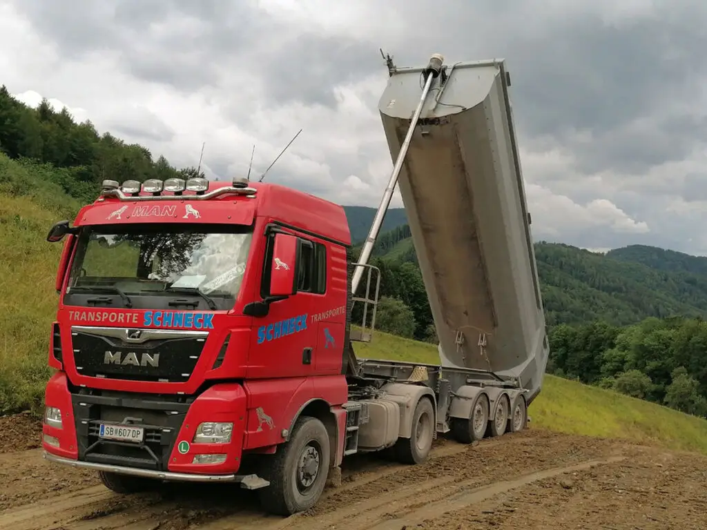 Schneck-Kipper beim Entladen von Schüttgut auf einer Baustelle in Hanglage.