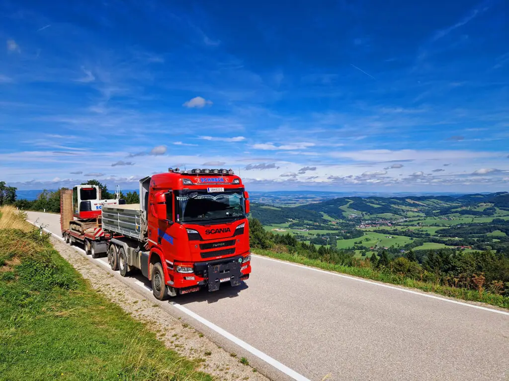 Sondertransport mit Tieflader auf einer Bergstraße mit weiter Aussicht über das Mostviertel.
