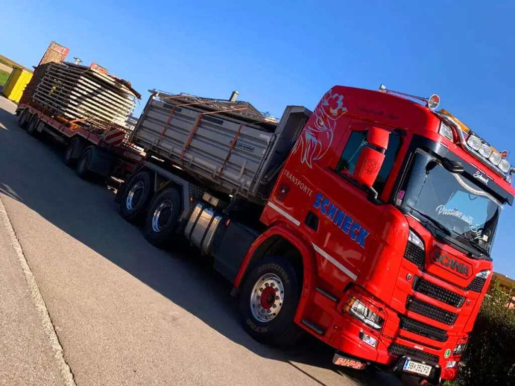 Scania-LKW mit Tieflader beim Transport eines großen Gittercontainers oder Anlagenteils.