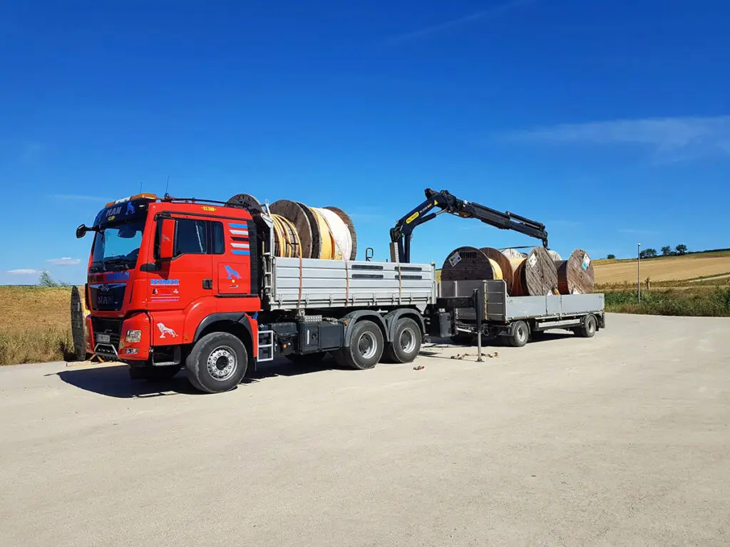 Kran-LKW beim Transport großer Betonrohre und Bauteile für Infrastrukturprojekte.