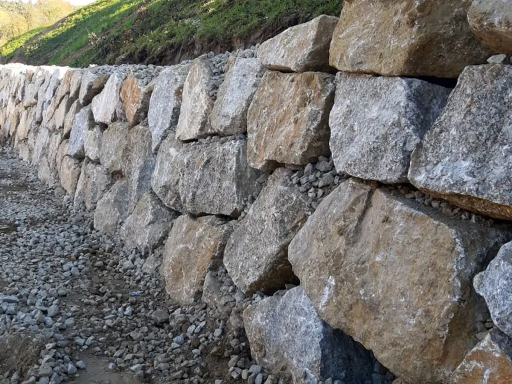 Detailansicht einer Wurfsteinmauer aus großen Natursteinen mit Schotterhinterfüllung.
