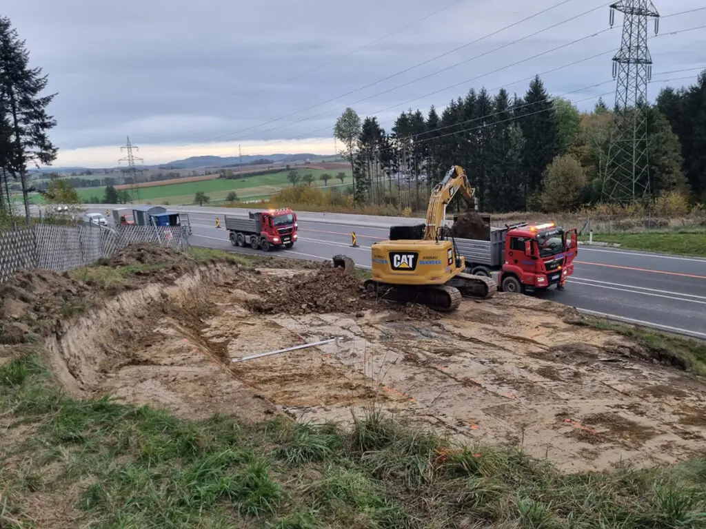 Straßenbauarbeiten mit Raupe und LKW zur Herstellung einer neuen Verkehrsfläche.